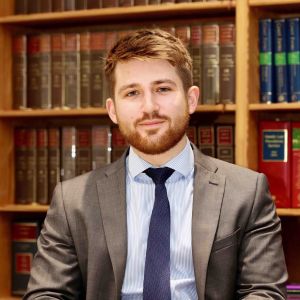 Bearded young man sat in front of legal bookcase